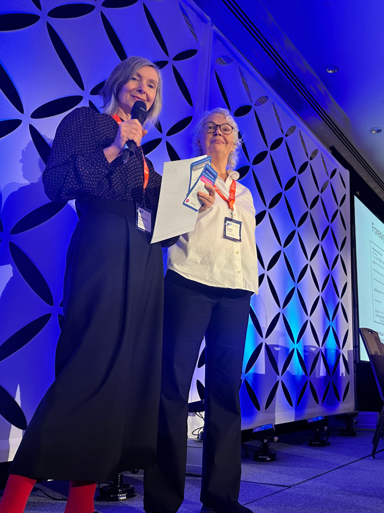 Two female presenters sharing research and engaging with the audience on stage at a prior Environmental Flows Conference.