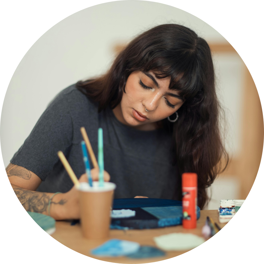 An indigenous artist working on a graphic layout at a desk, representing community artwork submissions for the Environmental Flows Conference in Kelowna, B.C.